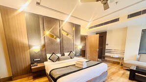 A modern hotel room with a large bed, wooden flooring, a ceiling fan, and a TV. - Hotel Holiday international (Purnia)