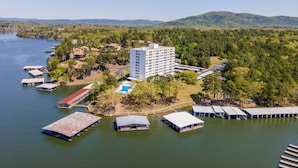 Vista aérea de un resort junto al lago, con un edificio grande, varias lanchas amarradas y una piscina.