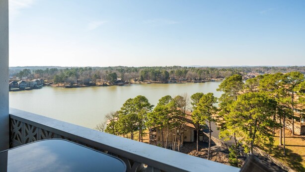Un balcón con vista a un lago, rodeado de árboles y edificios.