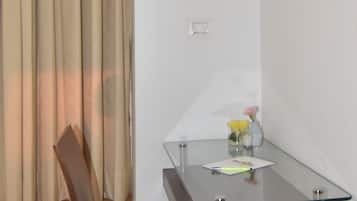 Una habitación pequeña y moderna con una mesa de vidrio, una silla de madera y un florero con flores.