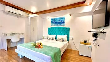 Un dormitorio con cama, escritorio, refrigerador pequeño y televisor.