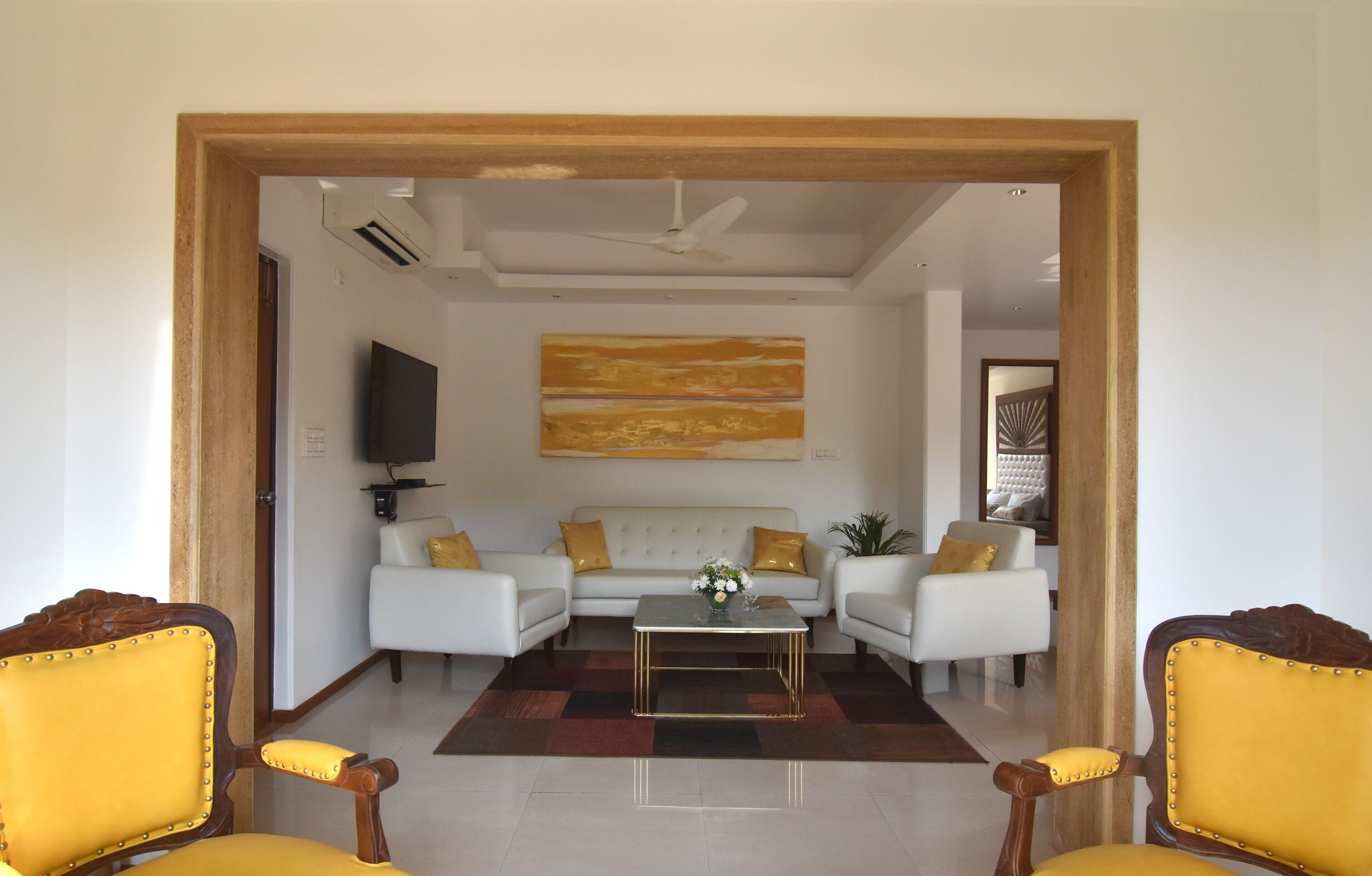 A living room with a sofa set, a coffee table, and two yellow chairs.