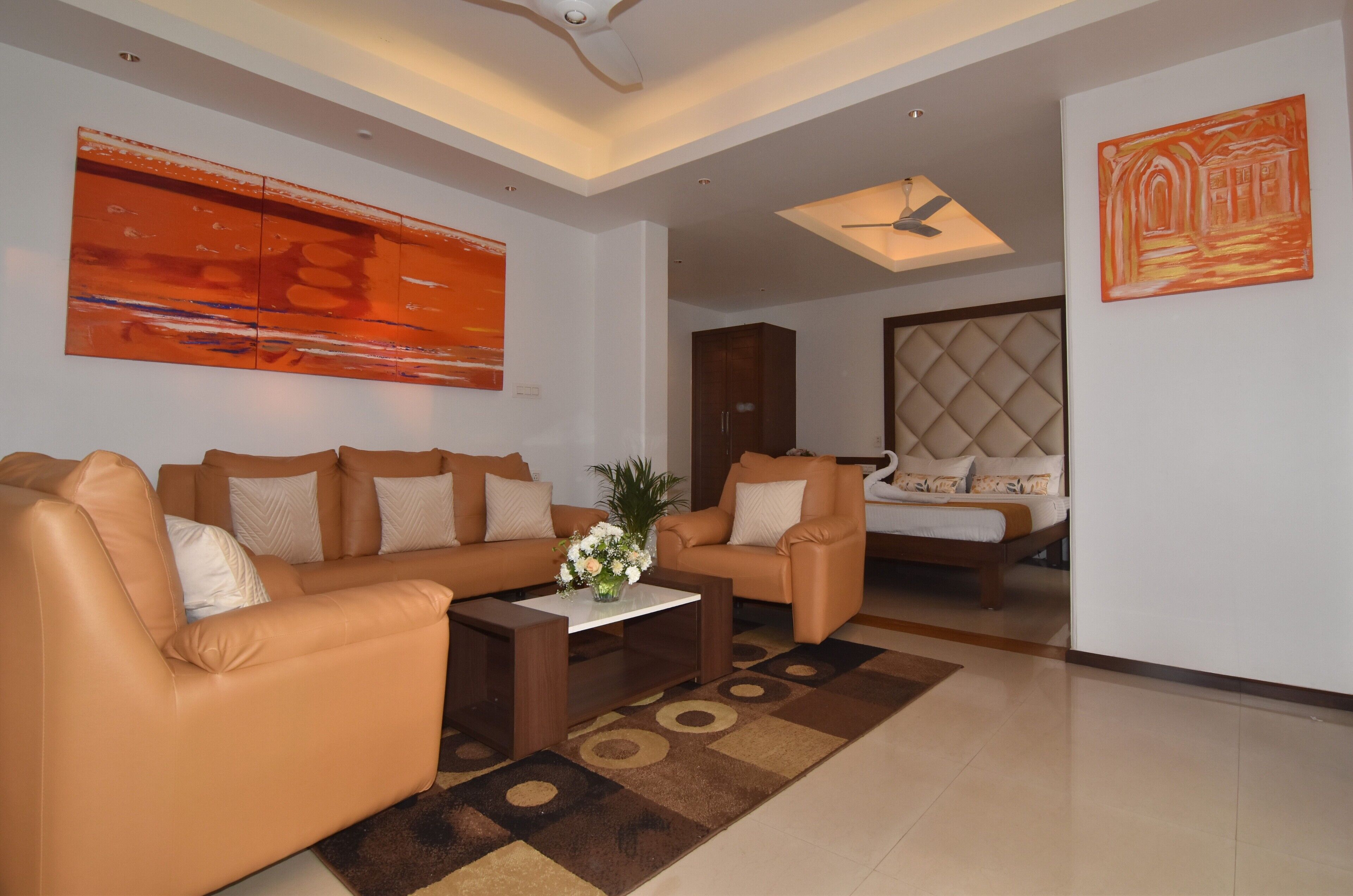 A modern living room with a sofa set, a coffee table with a floral centerpiece, and a decorative rug.