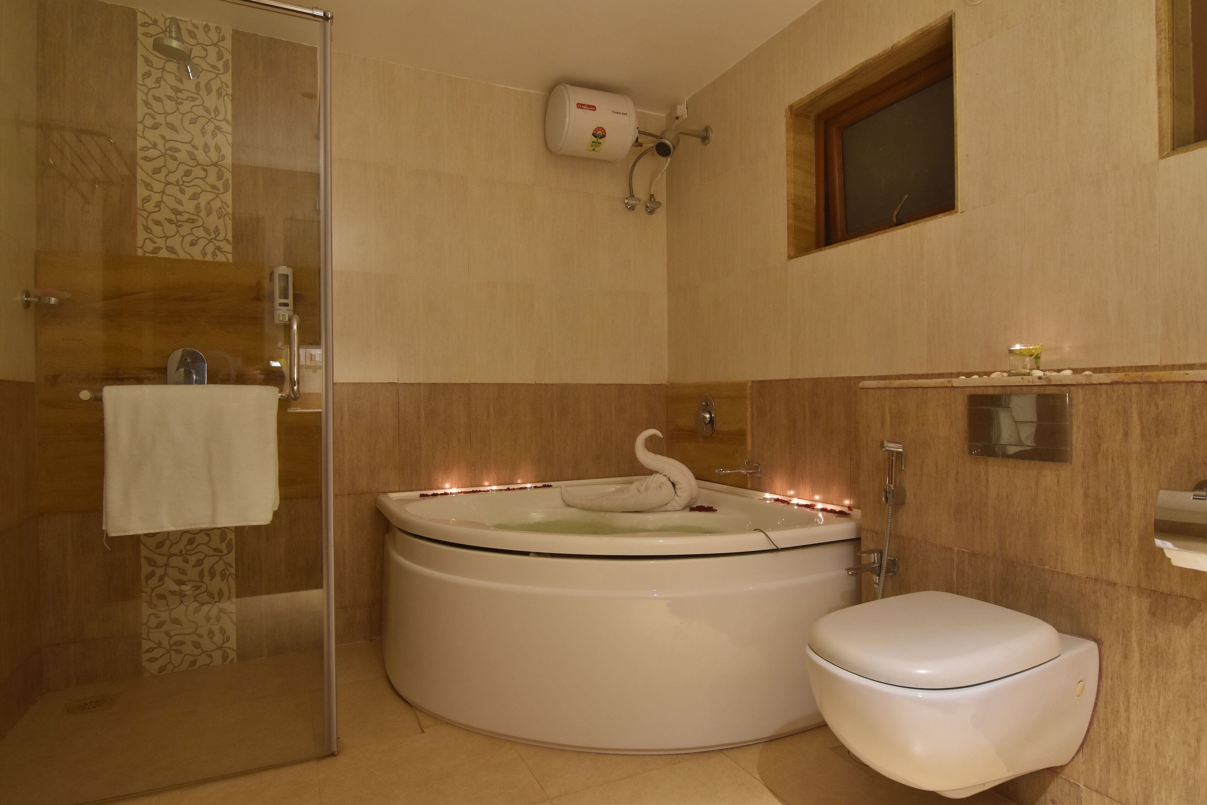 A bathroom with a glass-enclosed shower, a white bathtub with a swan-shaped bath mat, and a toilet.