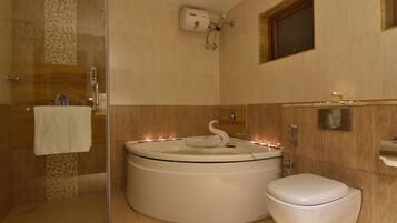 A bathroom with a glass-enclosed shower, a white bathtub with a swan-shaped bath mat, and a toilet.