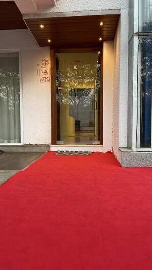 A building entrance with a red carpet, a glass door, and a sign with text. - Beach Paradise Miramar Goa (Panaji)