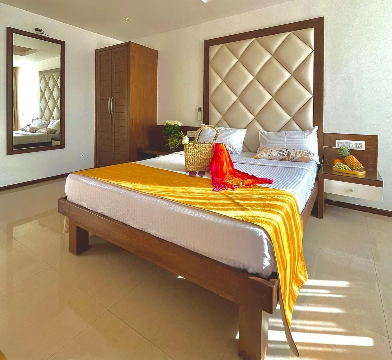 Una habitación de hotel con una cama grande, un armario, una mesita de noche y un espejo.