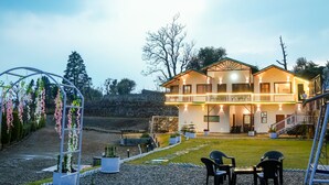 A two-story building with a balcony, surrounded by a gravel garden with potted plants and a seating area. - Monal meadows (Vijraula, Saikhola)