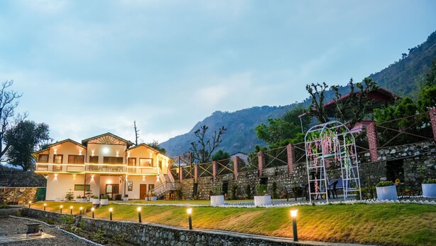 A two-story building with a balcony, stone walls, and a garden area with potted plants. - Monal meadows (Vijraula, Saikhola)
