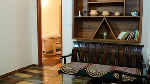 A traditional Japanese-style room with tatami flooring, a low wooden table, and matching chairs. A wooden shelf with decorative items and books is mounted on the wall. - Monal meadows (Vijraula, Saikhola)