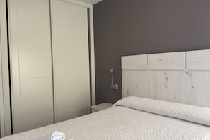 Un dormitorio con una cama, un armario y una mesita de noche.