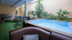 Ein Poolbereich mit Grill, Sitzgelegenheiten und diversen Pflanzen.