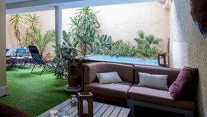 Ein gemütlicher Patio-Bereich mit Pool, grünem Kunstrasen und verschiedenen Topfpflanzen.