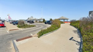 A parking lot with cars, a gazebo, and a building with a peaked roof. - Across From Beach | Renovated | Parking (Hampton)