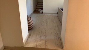Un couloir étroit avec un plancher en bois et un mur blanc.