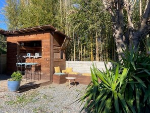 Une cabane en bois dotée d’un patio comprenant une table et des chaises, le tout entouré de verdure.