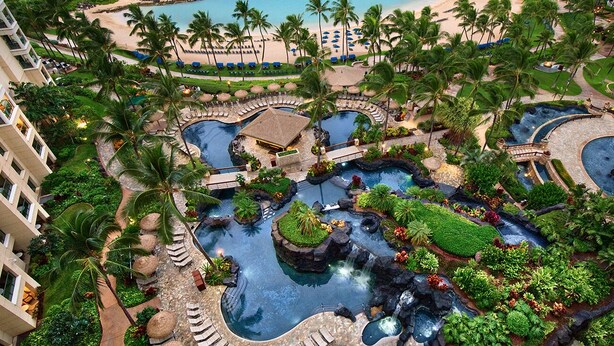 A resort with multiple swimming pools, palm trees, and a beach area.