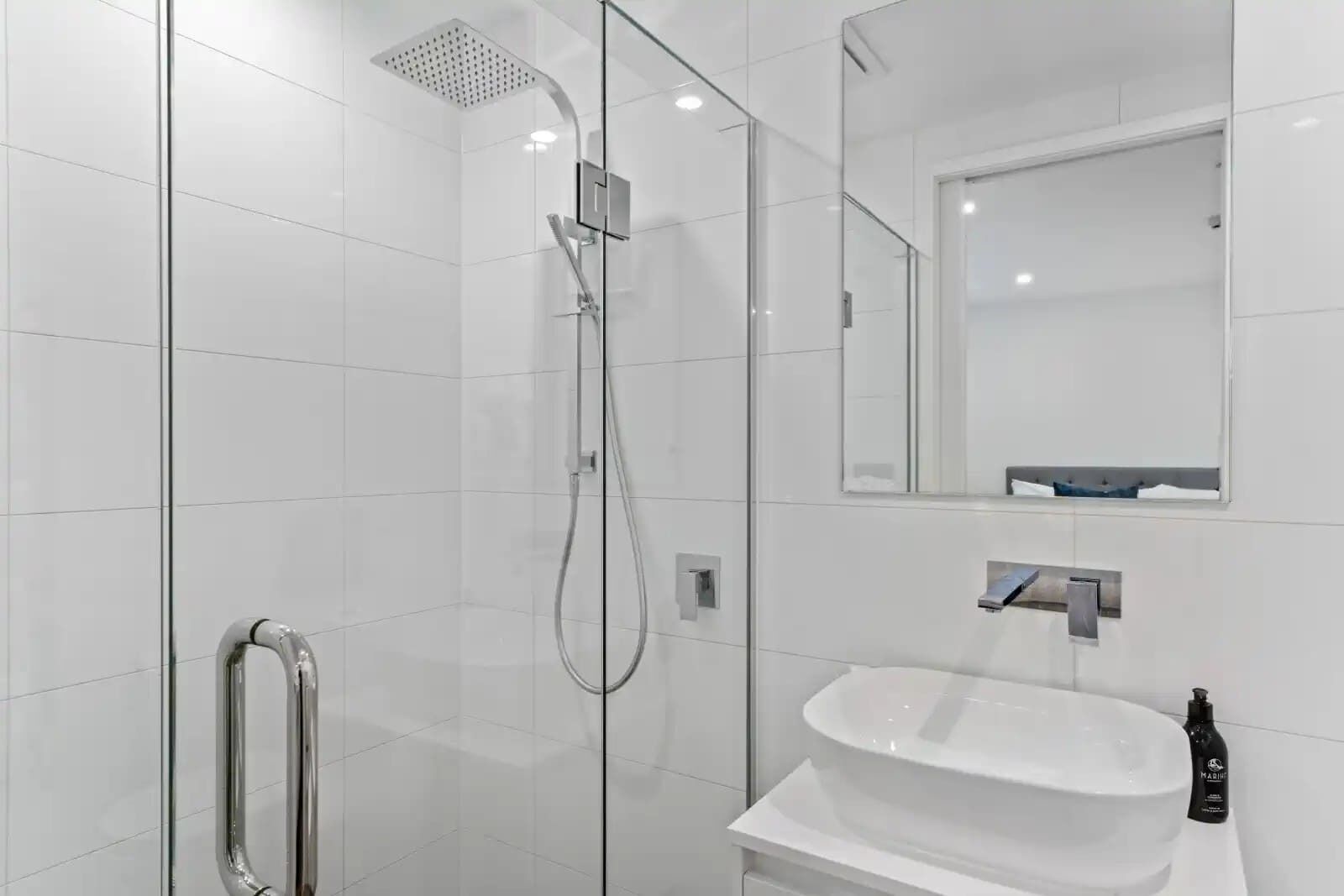 A modern bathroom with a glass-enclosed shower, a white sink, and a mirror above the sink.