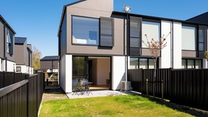 Ett modernt hus i två våningar med en uteplats, en satellitmottagare och en inhägnad trädgård.