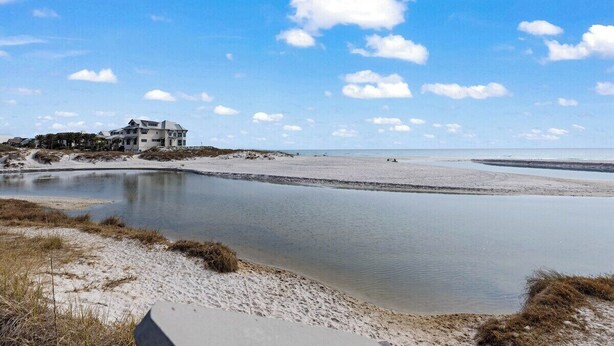 Een landhuis aan de kust, met een zandstrand en rustig water.