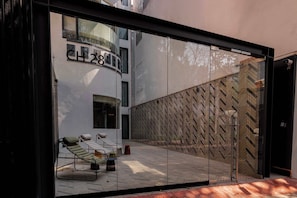 A modern building with a glass facade, a visible interior with a lounge area, and a herringbone-patterned wall.