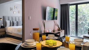 A modern hotel room with a bed, breakfast setup, a TV, and a balcony with a view. - Capitalia Hipódromo | Skyline Peace, Seamless Stay (Ciudad de México)
