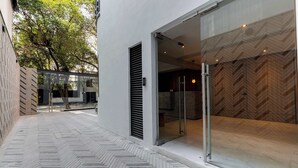 A modern building with a herringbone-patterned floor, a glass door entrance, and a view of a wooden interior. - Capitalia Hipódromo | Skyline Peace, Seamless Stay (Ciudad de México)