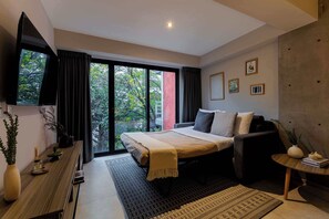A modern bedroom with a bed, a TV, a desk, and a large window.