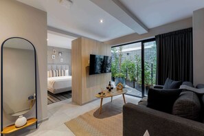 Une chambre d’hôtel moderne équipée d’un lit, d’une télévision, d’un canapé et d’un balcon agrémenté de plantes.