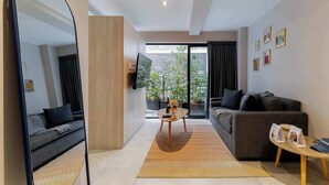 Un salon moderne avec un canapé, une table basse, un téléviseur et un grand miroir.
