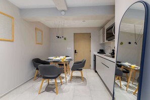 A modern kitchen with a dining area, featuring a round table, four chairs, and a large mirror.