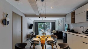 A modern kitchen with a dining area, a TV, and a sliding glass door leading to a balcony. - Capitalia | Your Sky-High Sanctuary in Condesa (Ciudad de México)