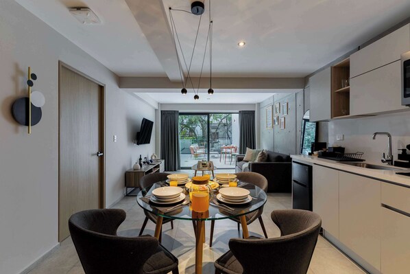 Une cuisine moderne avec un coin repas, un téléviseur et une porte-fenêtre coulissante donnant sur un balcon.