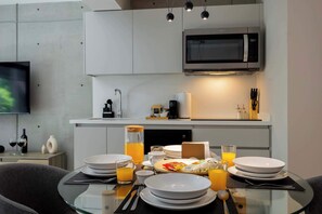 Une cuisine moderne équipée d’un four à micro-ondes, d’un évier et d’un coin repas avec des assiettes, des verres et un verre de jus d’orange.
