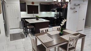 Una cocina moderna con armarios oscuros, una isla central y una zona de comedor con mesa y sillas.