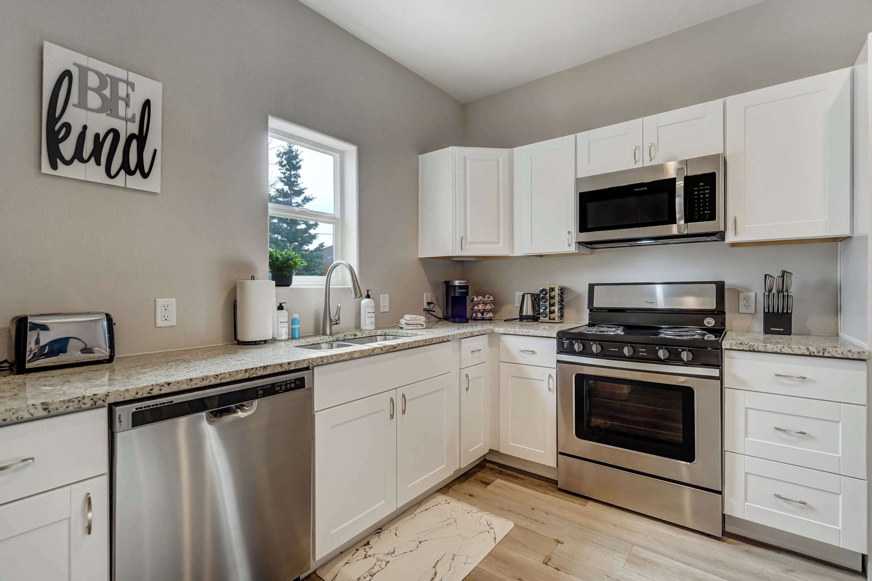 A modern kitchen with white cabinets, stainless steel appliances, and a marble backsplash.
