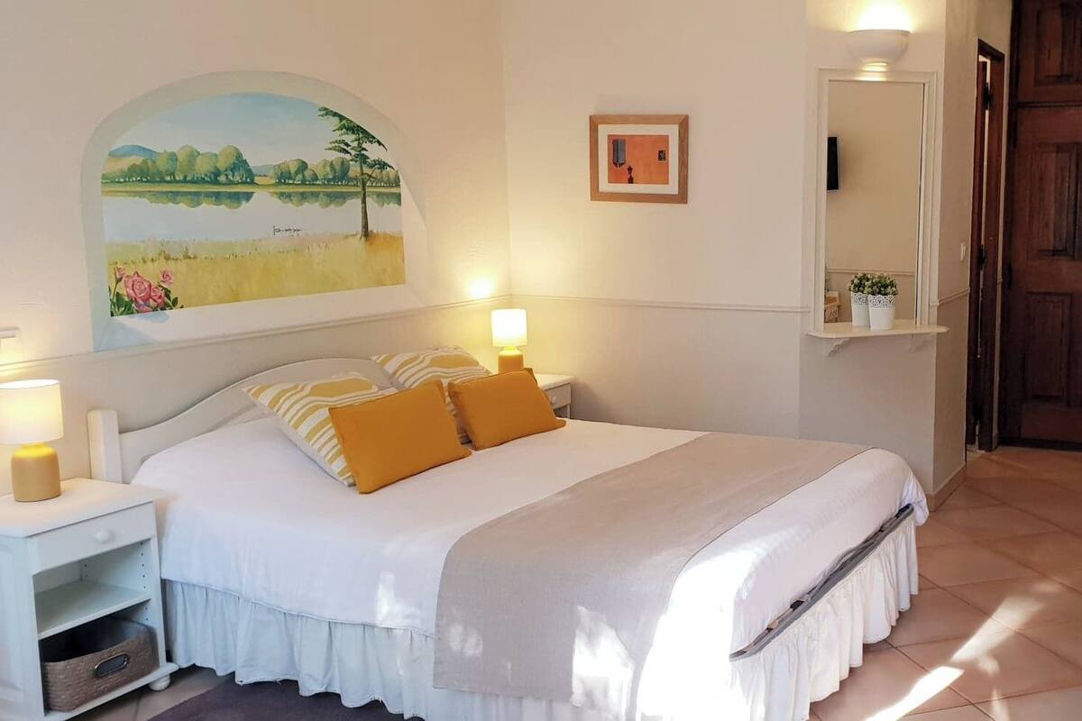 A neatly arranged bedroom with a bed, bedside tables, a mirror, and a door.