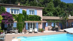 A two-story building with a swimming pool, outdoor seating, and lush greenery. - le Mas des Cigales (Tourrettes-sur-Loup)