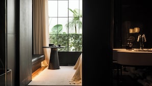 Un baño moderno con un ventanal grande, un lavabo redondo y un banco junto a la ventana.