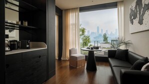 Una sala de estar moderna con vista a la ciudad, una mesa de centro redonda, un sofá y una silla.