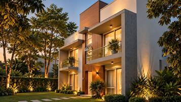 Un edificio moderno de dos pisos con balcón, ventanas amplias y un jardín cuidado.
