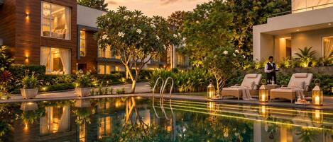 A modern hotel with a swimming pool, outdoor seating, and lush landscaping.
