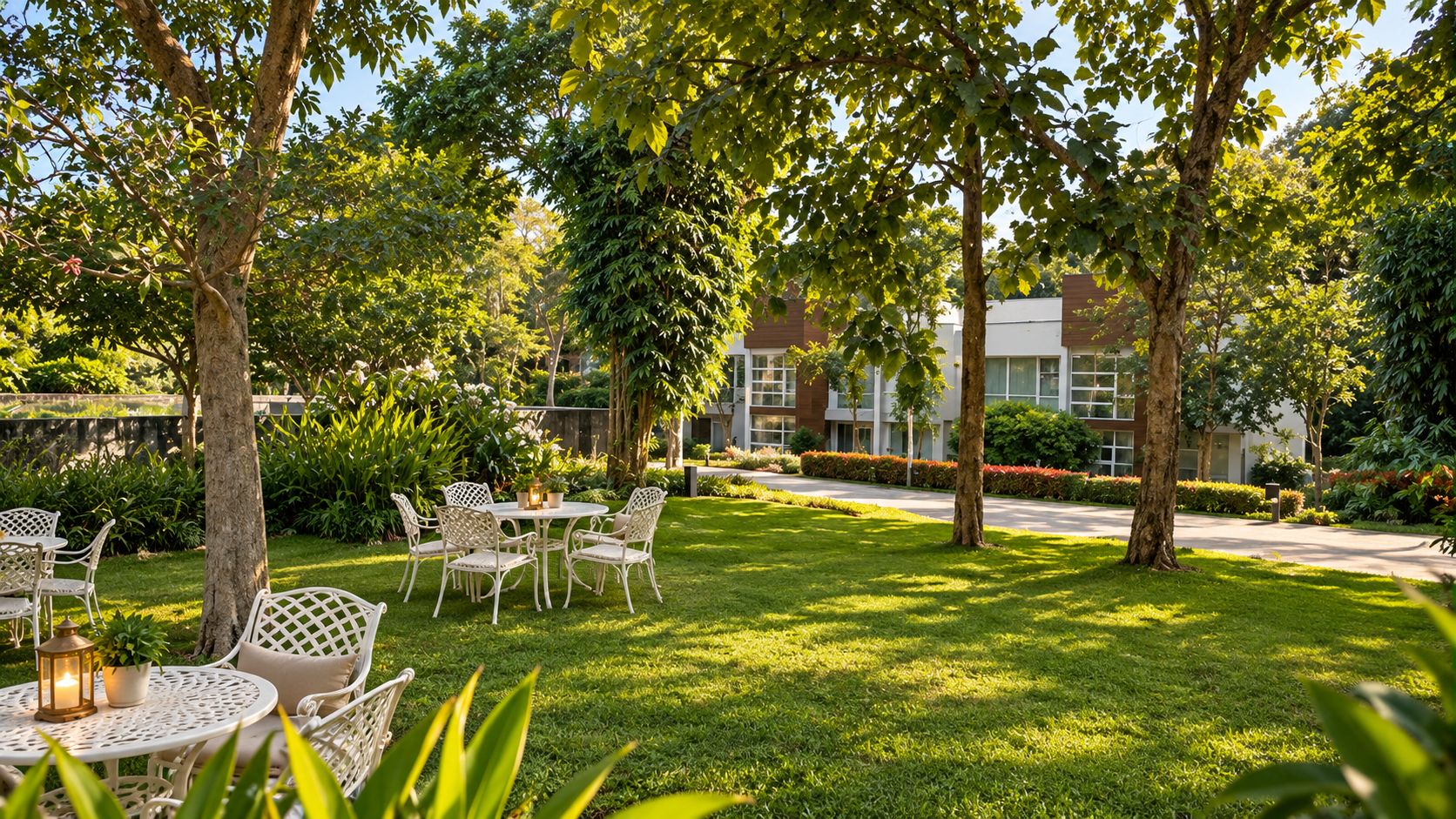 An outdoor seating area with white wicker furniture, surrounded by lush greenery and trees.