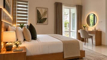A modern bedroom with a large bed, bedside table with a lamp, a desk with a chair, and a window with curtains.