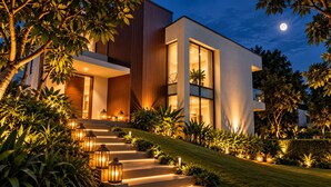A modern house with a staircase leading to the entrance, surrounded by lush greenery and illuminated by warm lighting. - Lake Villas Premium Kandy (Kandy)