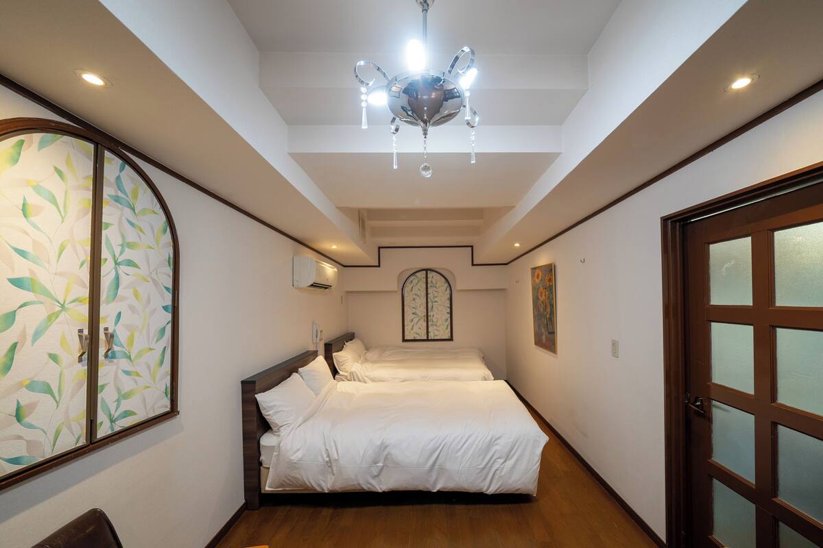 A hotel room with a large bed, a chandelier, a decorative wall, and a wooden floor.