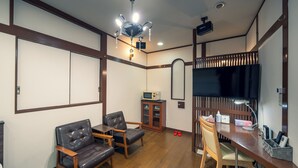 A room with a wooden desk, two leather chairs, a television, and a cabinet. - Grand Hotel Narita Airport (Narita)