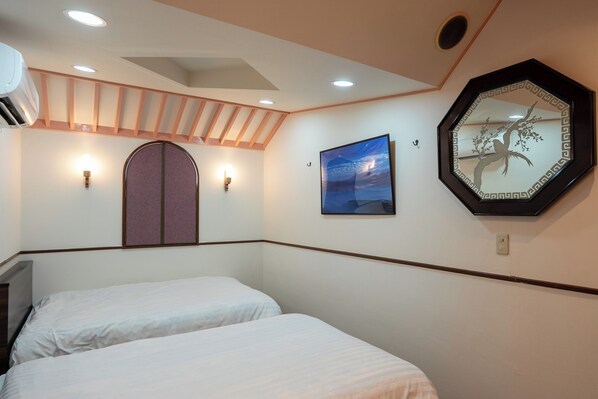 Une chambre d’hôtel avec deux lits, un grand miroir et un tableau accroché au mur.