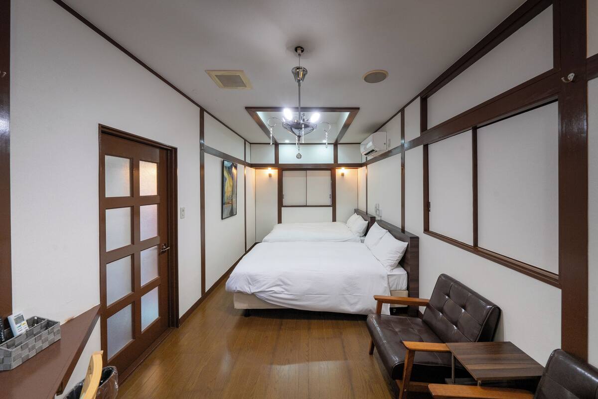 A hotel room with a bed, a sofa, a small table, and a wooden floor.
