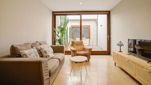 A living room with a sofa, armchair, TV, and a sliding glass door leading to an outdoor area. - Comtat Muro 1 by Renallorca (Muro)